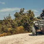 Modern ATV with fuel injection engine, riding on a road.