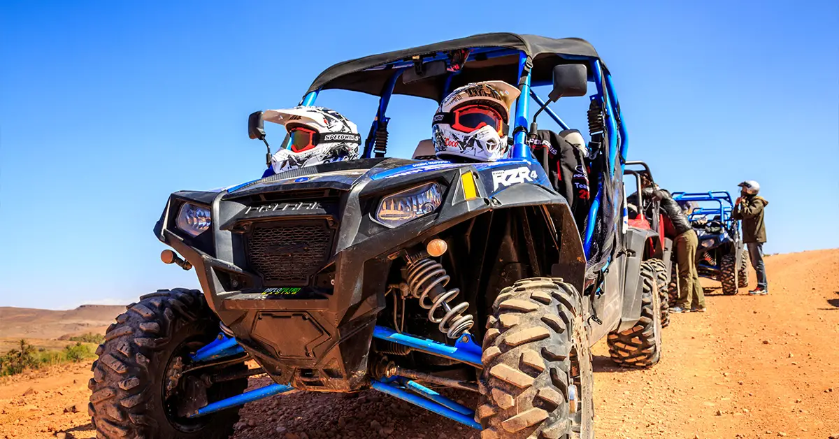 UTVs lined up in the desert, with a Polaris RZR in the front